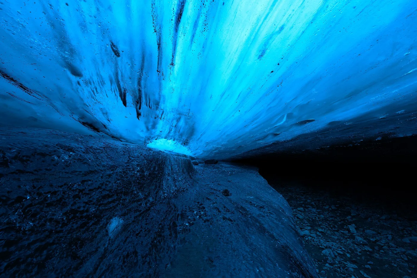 Light shining through the blue ice roof of a large chamber in a Vatnajökull ice cave on an Iceland ice cave day tour