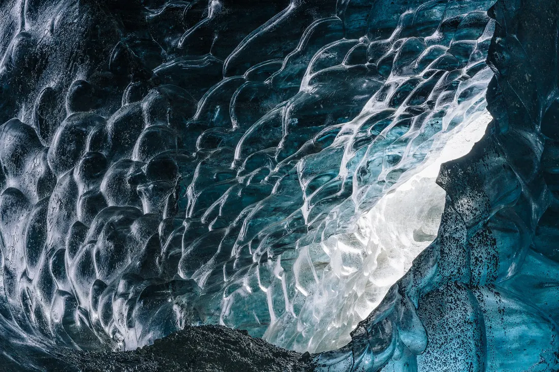 Scalloped blue and white ice at the mouth of an ice cave near Jökulsárlón on an Iceland ice cave day tour
